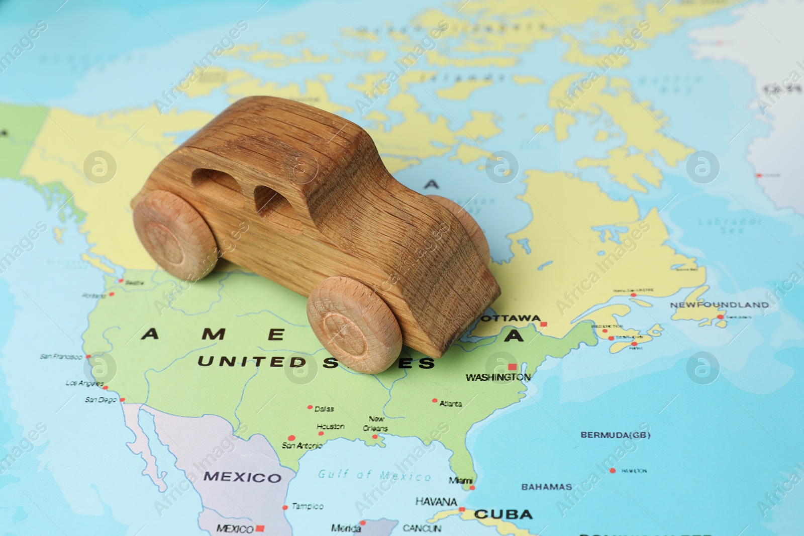 Photo of Wooden toy car on world map, closeup. Road trip