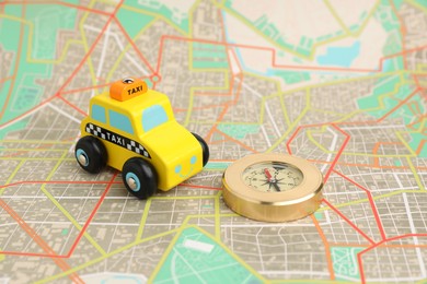 Photo of Yellow taxi car and compass on city map. Road trip