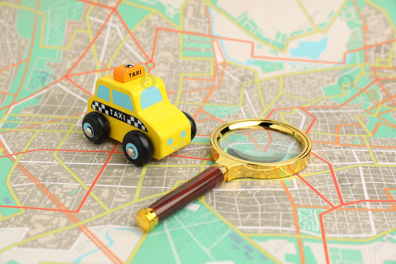 Photo of Yellow taxi car and magnifying glass on city map. Road trip