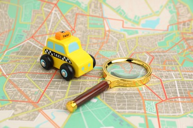 Photo of Yellow taxi car and magnifying glass on city map. Road trip