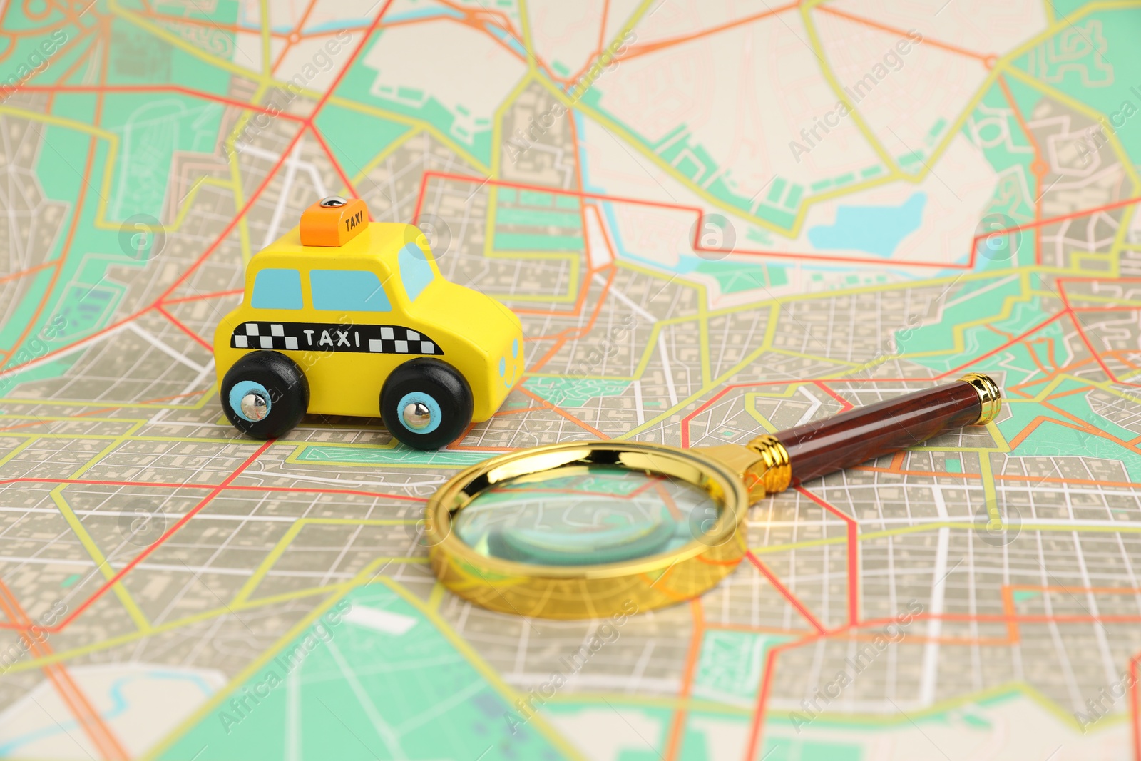 Photo of Yellow taxi car and magnifying glass on city map. Road trip