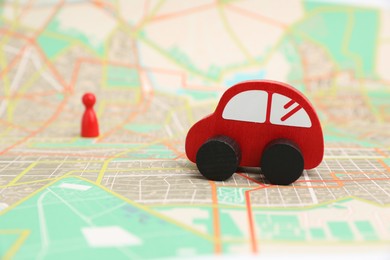 Photo of Red toy car and human figure on city map, selective focus. Road trip