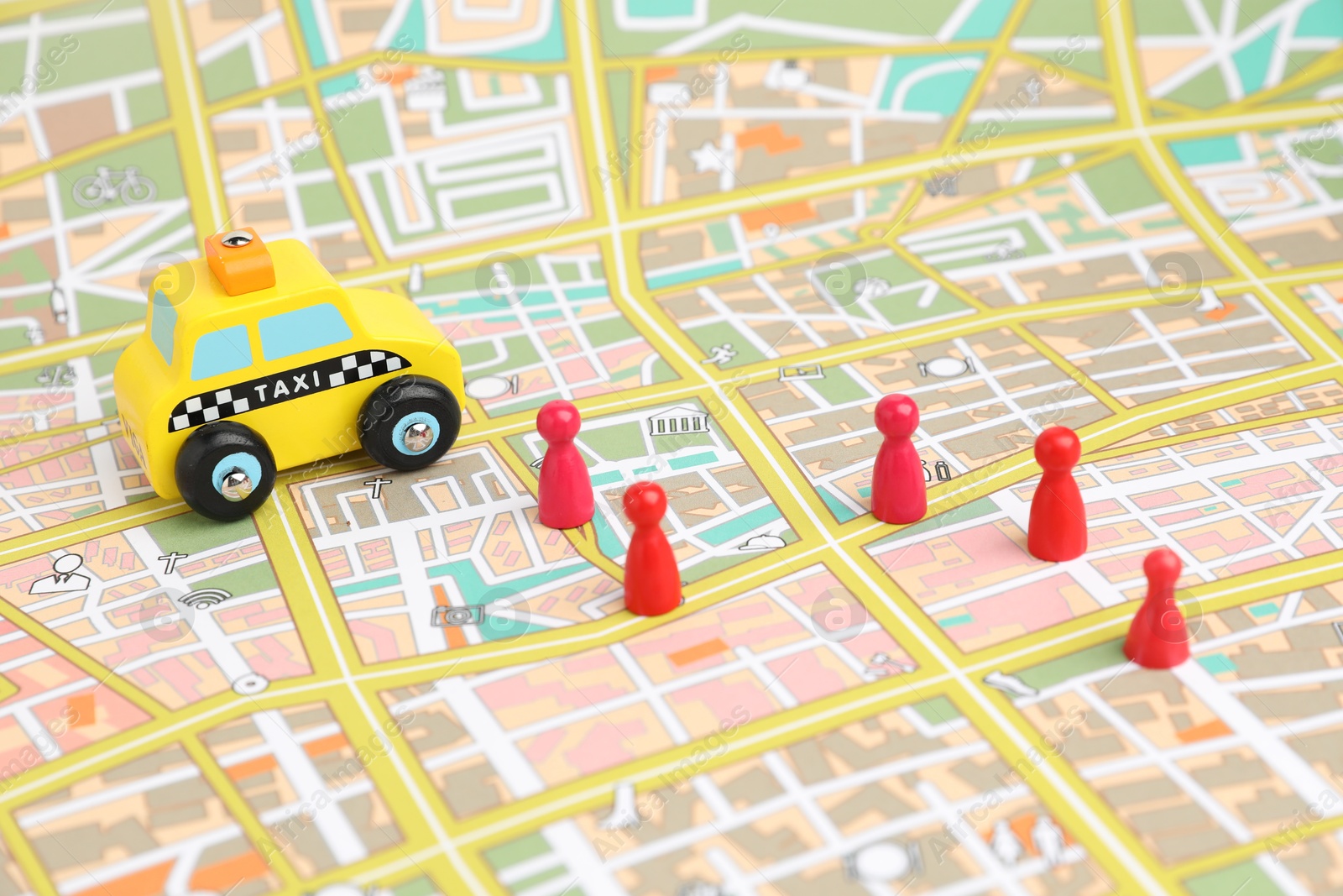 Photo of Yellow taxi car and red human figures on city map