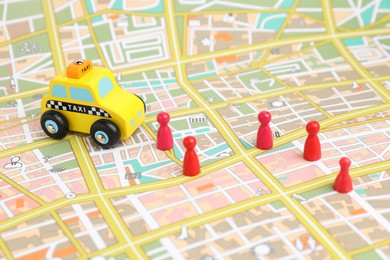 Photo of Yellow taxi car and red human figures on city map