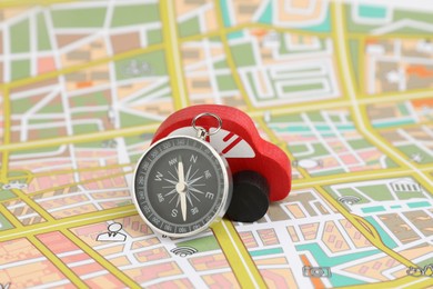 Photo of Red toy car and compass on city map. Road trip