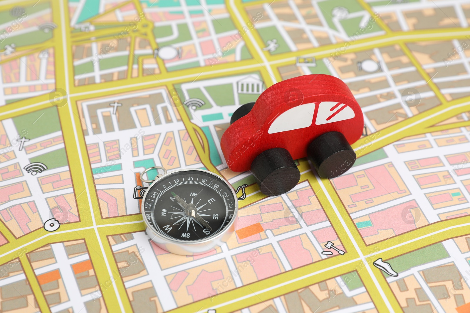 Photo of Red toy car and compass on city map. Road trip