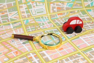 Photo of Red toy car and magnifying glass on city map. Road trip