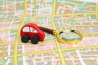 Photo of Red toy car and magnifying glass on city map. Road trip