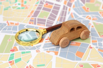 Photo of Wooden toy car and magnifying glass on city map. Road trip