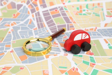 Photo of Red toy car and magnifying glass on city map. Road trip