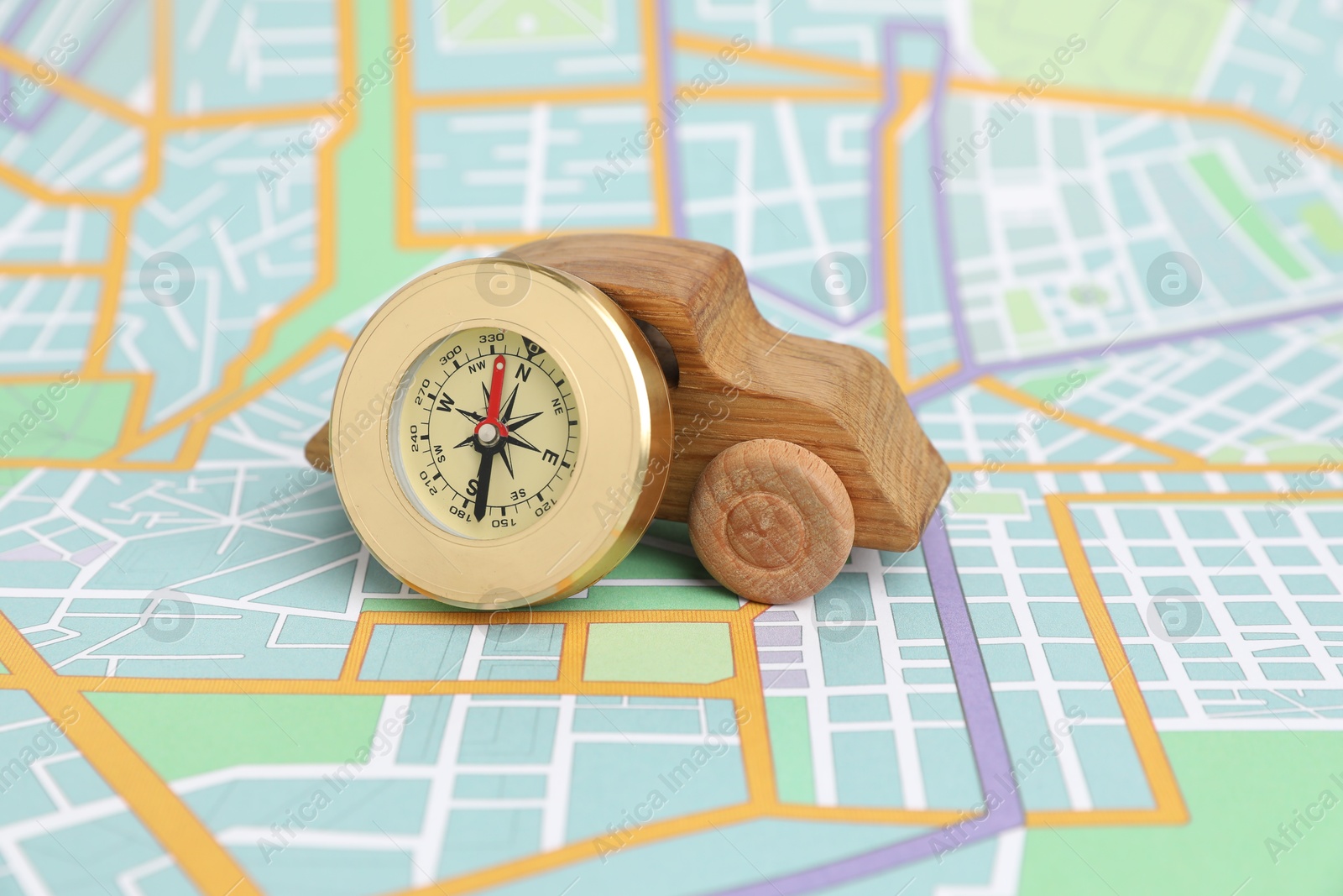 Photo of Wooden toy car and compass on city map. Road trip