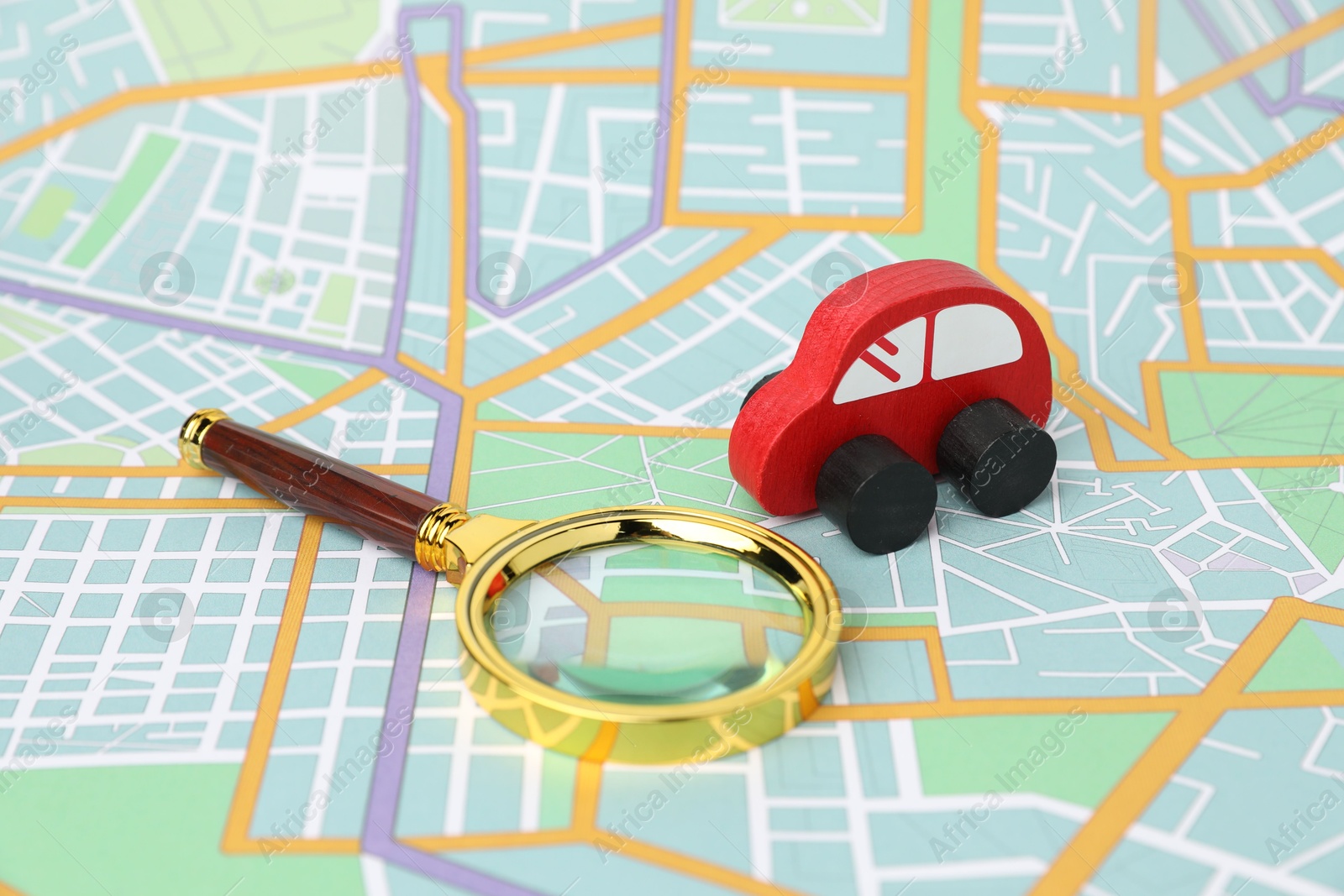 Photo of Red toy car and magnifying glass on city map. Road trip