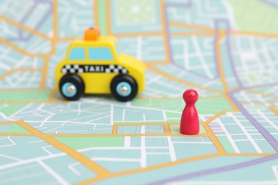 Photo of Yellow taxi car and red human figure on city map, selective focus. Road trip