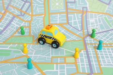 Photo of Yellow taxi car and colorful human figures on city map