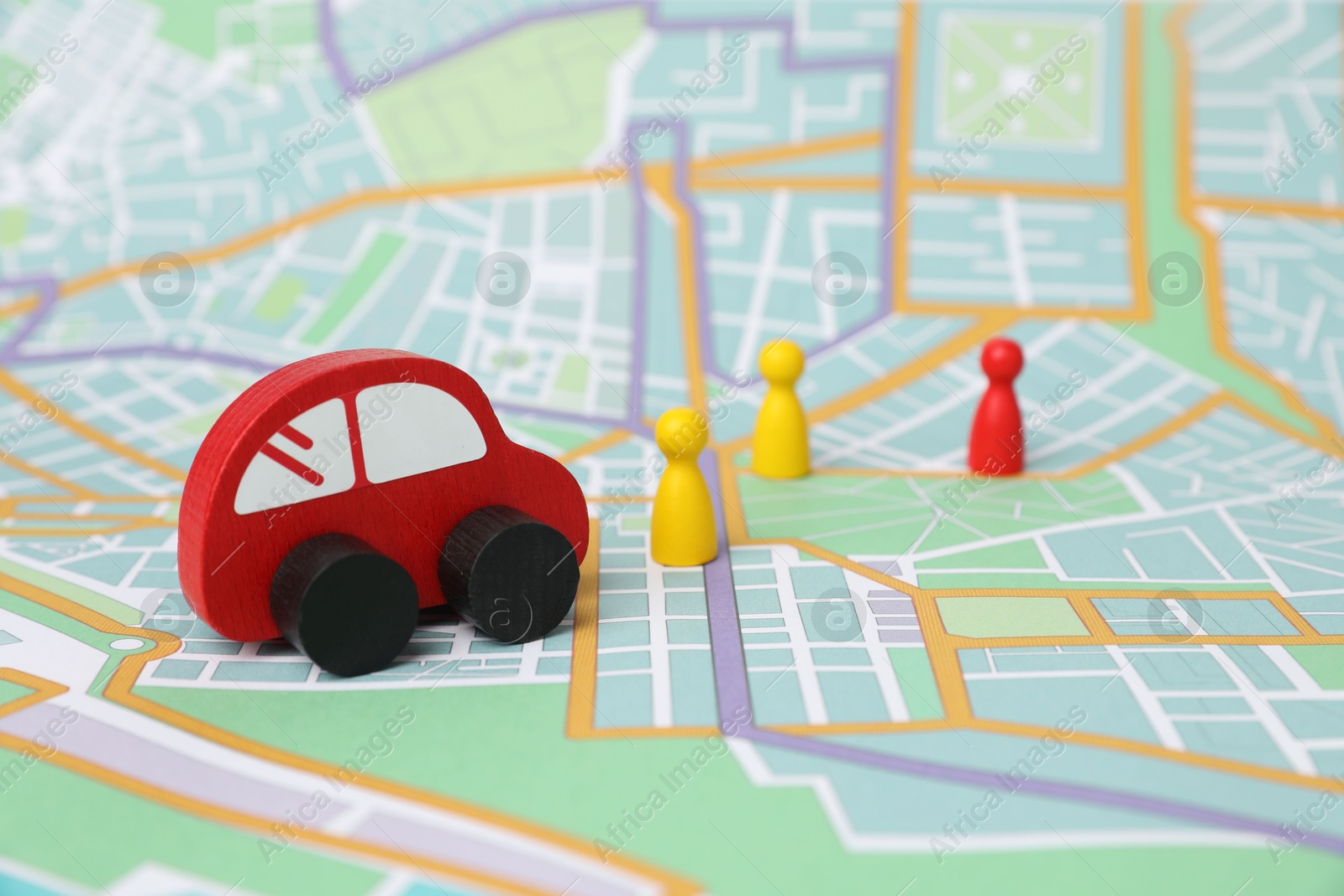 Photo of Red toy car and colorful human figures on city map. Road trip