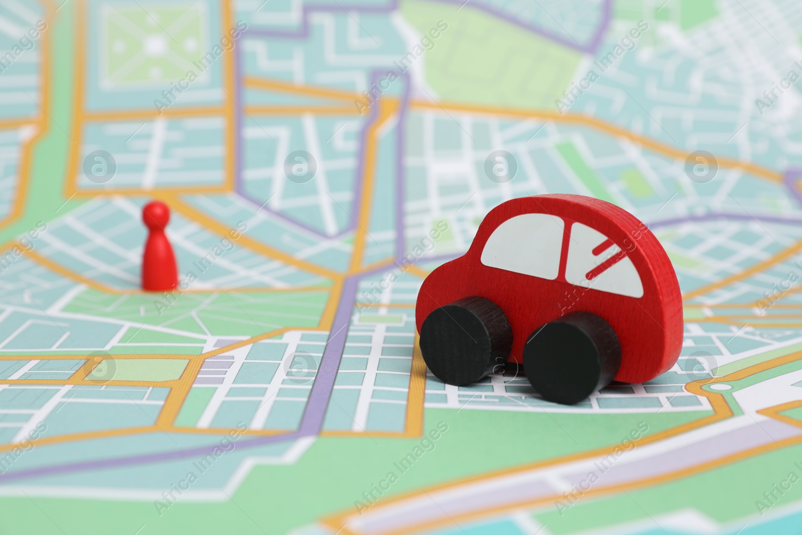 Photo of Red toy car and human figure on city map, selective focus. Road trip