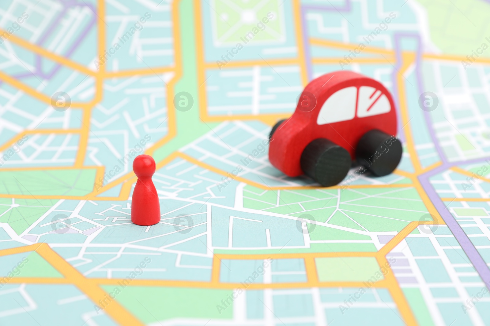 Photo of Red toy car and human figure on city map, selective focus. Road trip