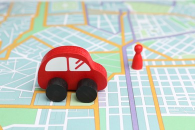 Photo of Red toy car and human figure on city map, selective focus. Road trip