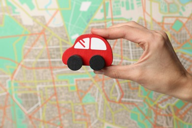 Photo of Woman with red toy car against city map, closeup. Road trip