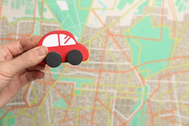 Photo of Woman with red toy car against city map, closeup. Road trip