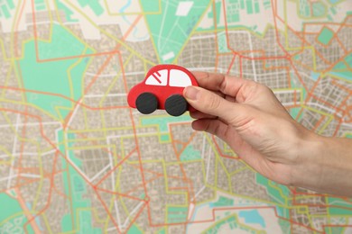 Photo of Woman with red toy car against city map, closeup. Road trip