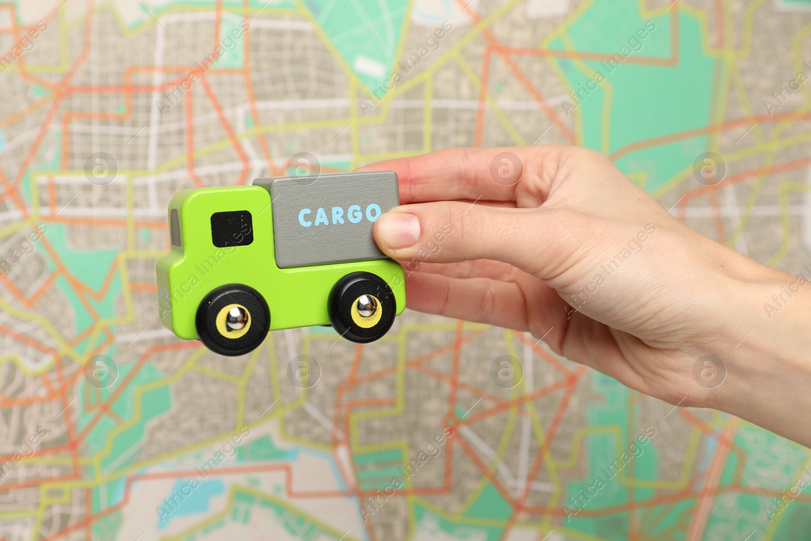 Photo of Woman with toy truck against city map, closeup. Logistics concept