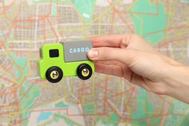 Photo of Woman with toy truck against city map, closeup. Logistics concept