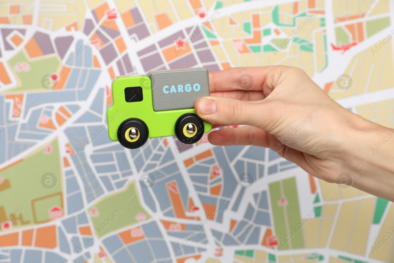 Photo of Woman with toy truck against city map, closeup. Logistics concept