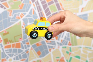 Photo of Woman with yellow taxi car against city map, closeup