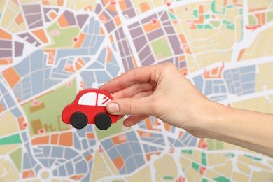 Photo of Woman with red toy car against city map, closeup. Road trip