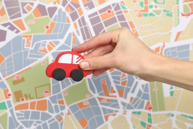 Photo of Woman with red toy car against city map, closeup. Road trip