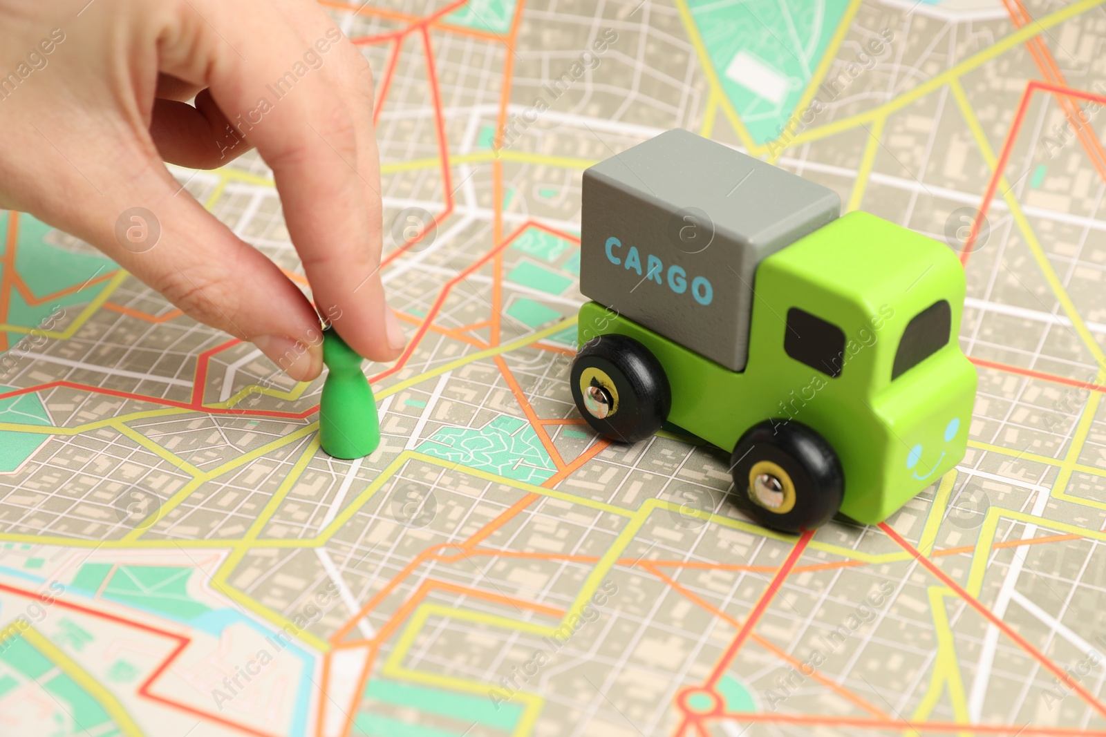 Photo of Woman putting game piece on city map near toy truck, closeup. Road trip