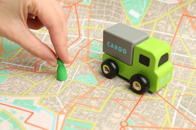 Photo of Woman putting game piece on city map near toy truck, closeup. Road trip