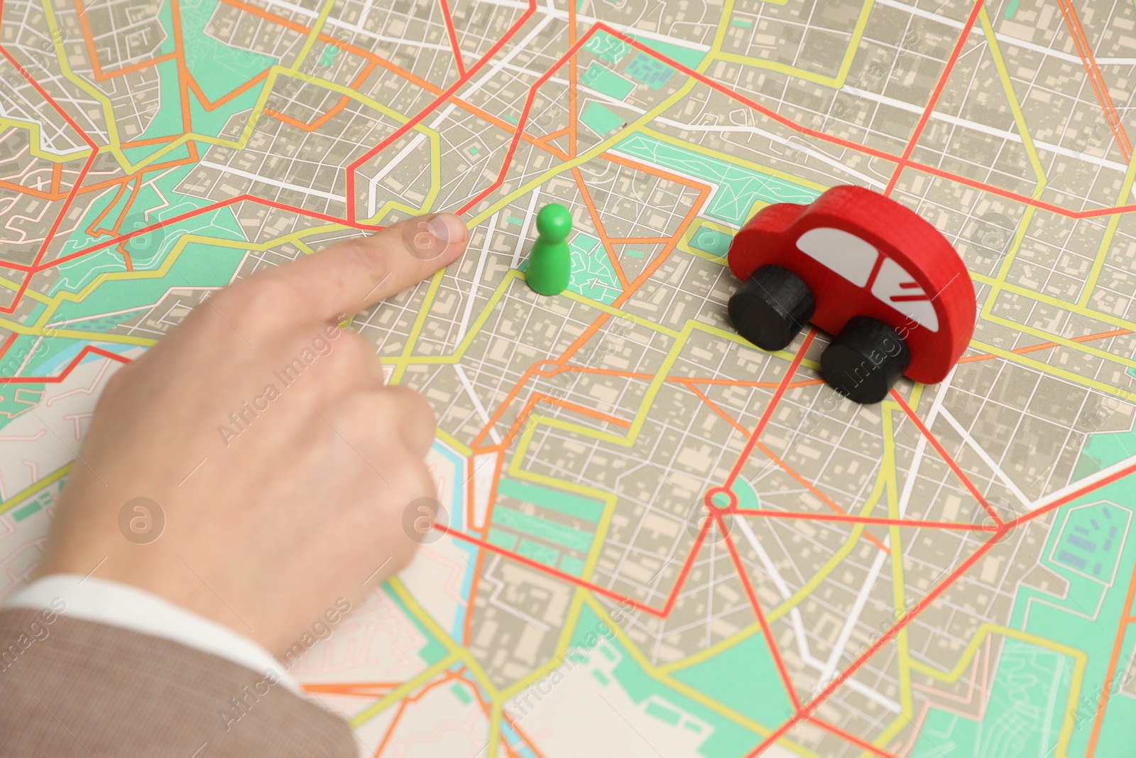 Photo of Woman pointing at city map near human figure and toy car, closeup. Road trip