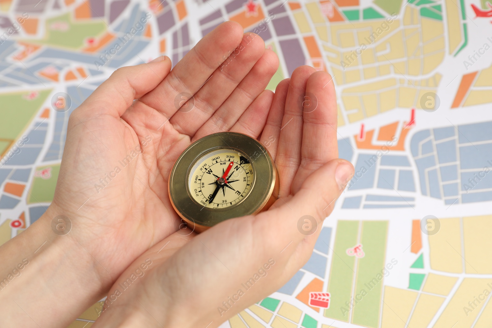 Photo of Woman holding compass over city map, closeup