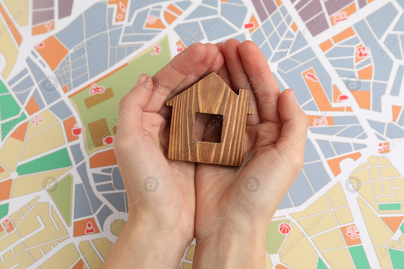 Photo of Woman holding wooden house model over city map, top view. Accommodation search