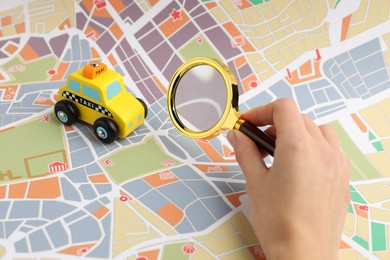 Photo of Woman looking at city map through magnifying glass, closeup. Road trip