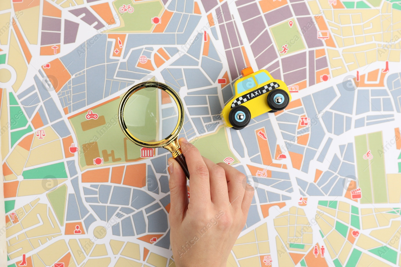 Photo of Woman looking at city map through magnifying glass, top view. Road trip