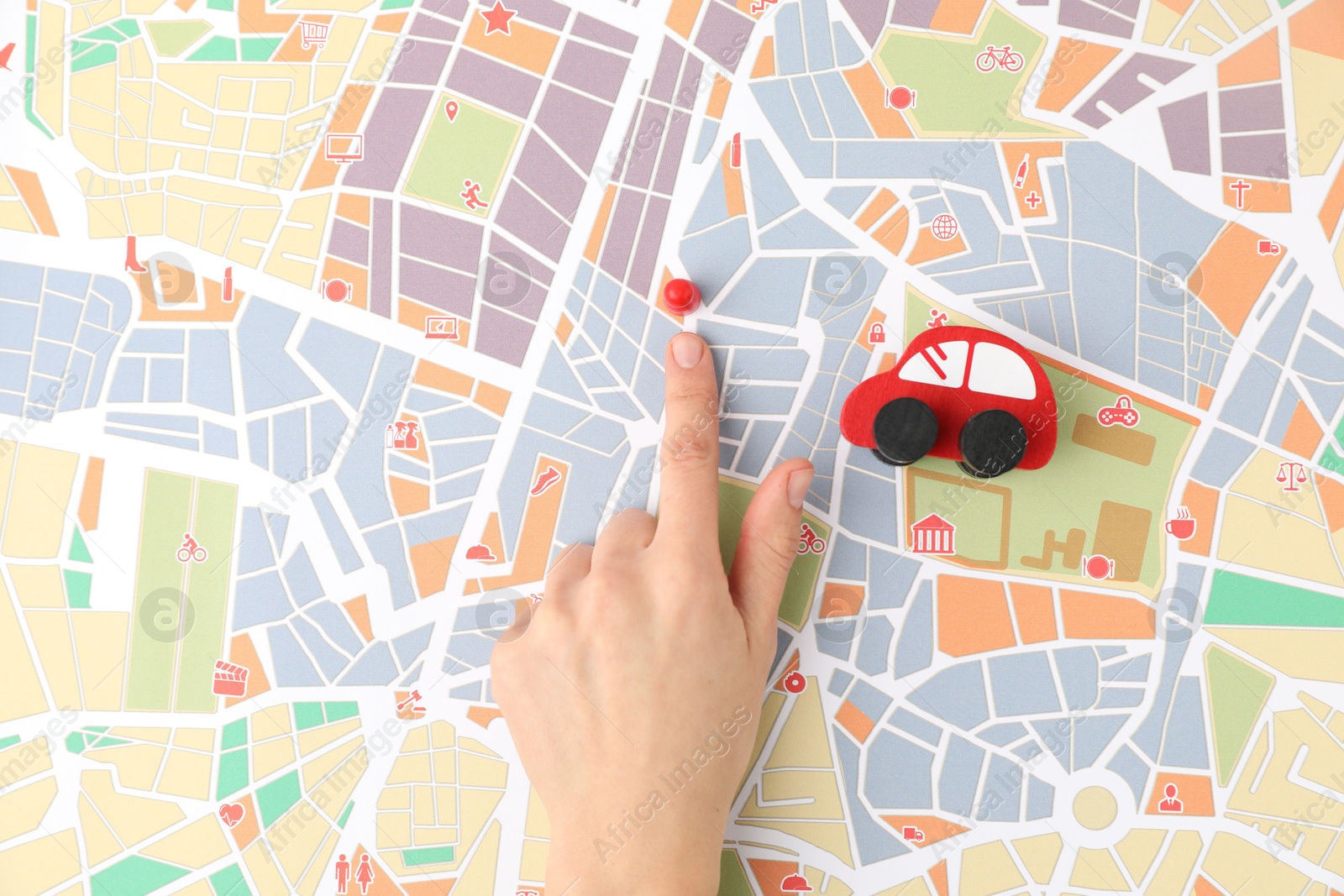 Photo of Woman pointing at city map near human figure and toy car, top view. Road trip