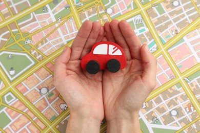 Photo of Woman holding red toy car over city map, top view. Road trip