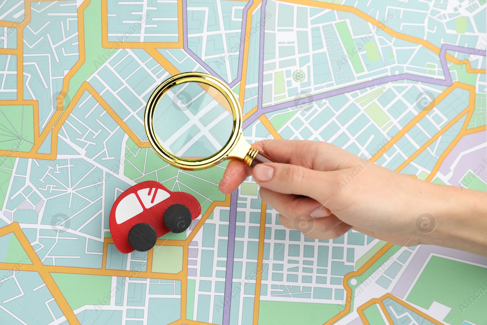 Photo of Woman looking at city map through magnifying glass, top view. Road trip