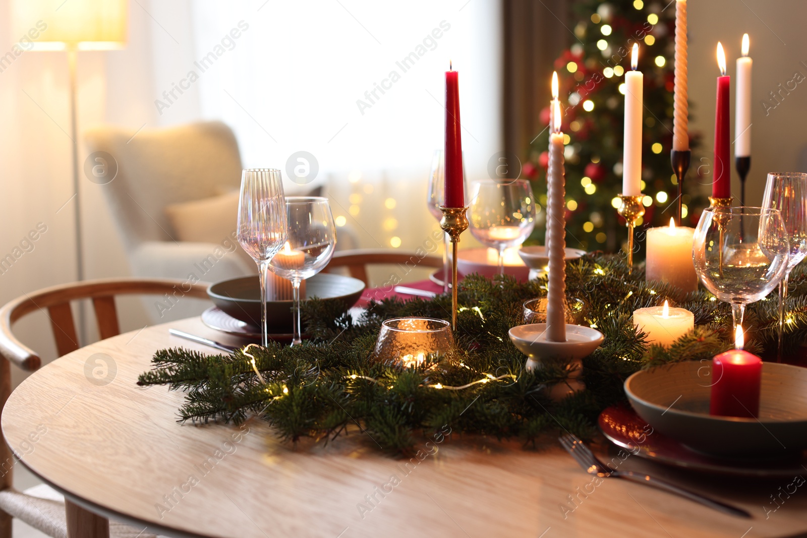 Photo of Festive table setting in room decorated for Christmas, closeup. Bokeh effect