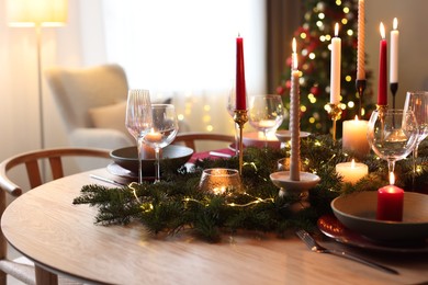 Photo of Festive table setting in room decorated for Christmas, closeup. Bokeh effect