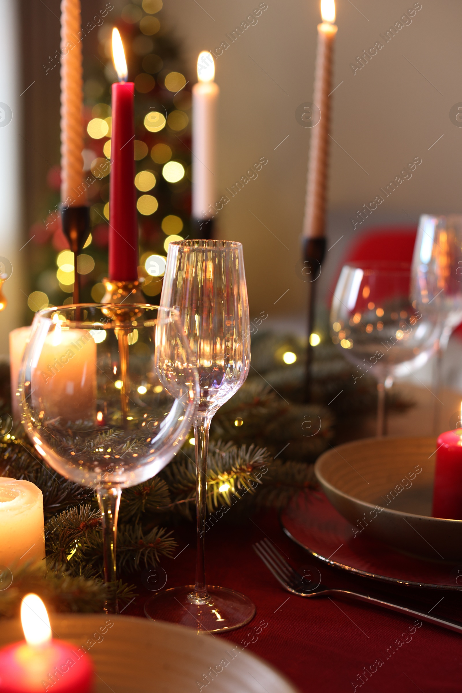 Photo of Festive table setting in room decorated for Christmas, closeup. Bokeh effect