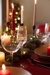 Photo of Festive table setting in room decorated for Christmas, closeup. Bokeh effect