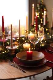 Photo of Festive table setting in room decorated for Christmas, closeup. Bokeh effect