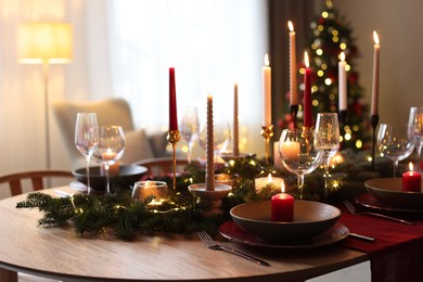 Photo of Festive table setting in room decorated for Christmas, closeup. Bokeh effect