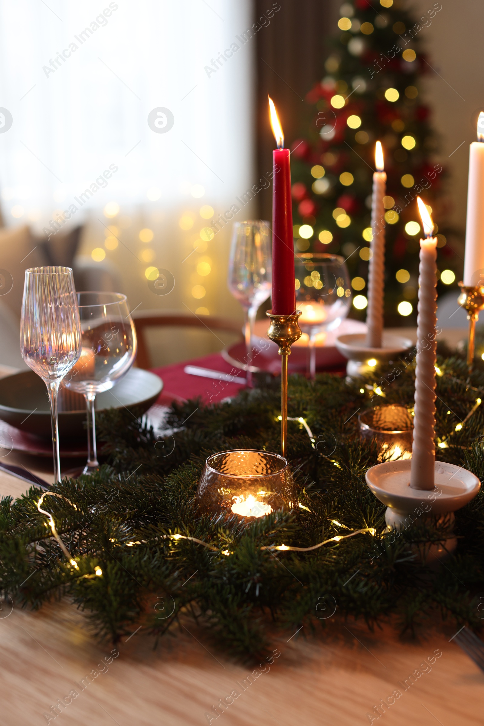 Photo of Festive table setting in room decorated for Christmas, closeup. Bokeh effect