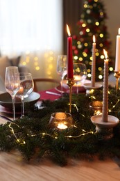 Photo of Festive table setting in room decorated for Christmas, closeup. Bokeh effect