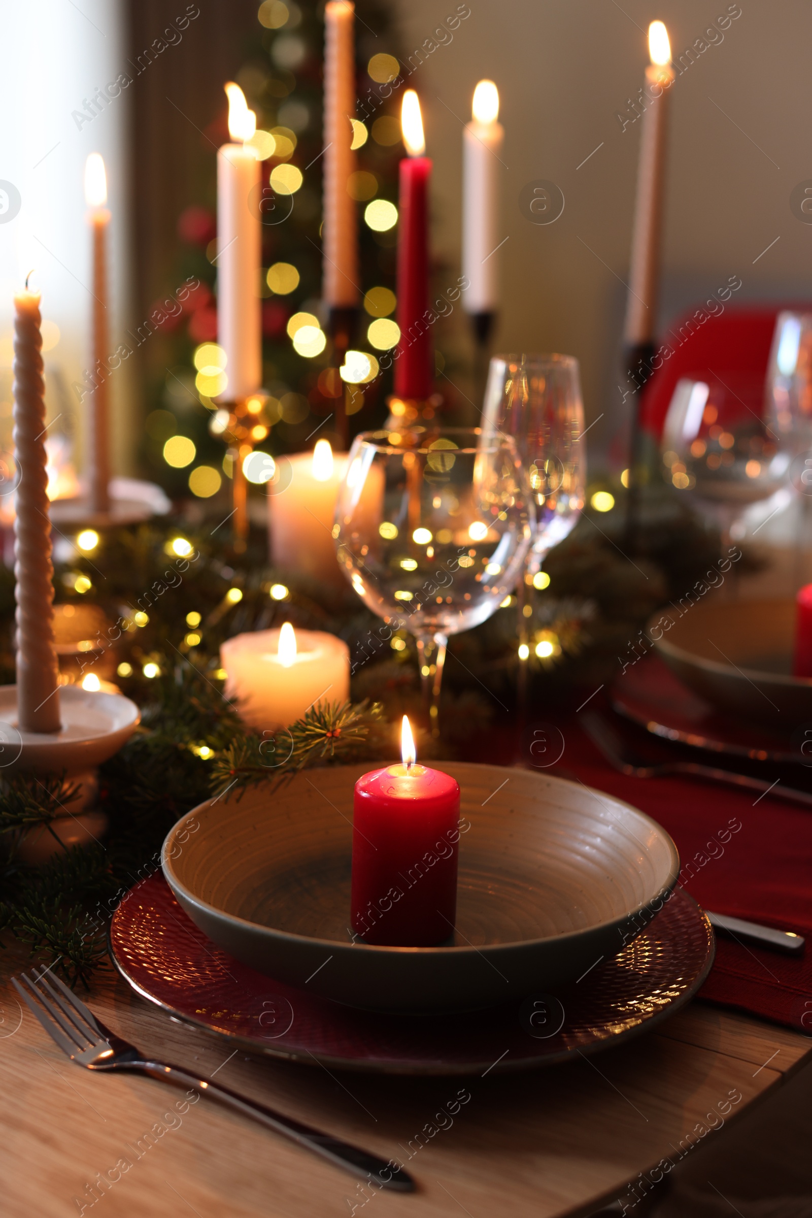 Photo of Festive table setting in room decorated for Christmas, closeup. Bokeh effect